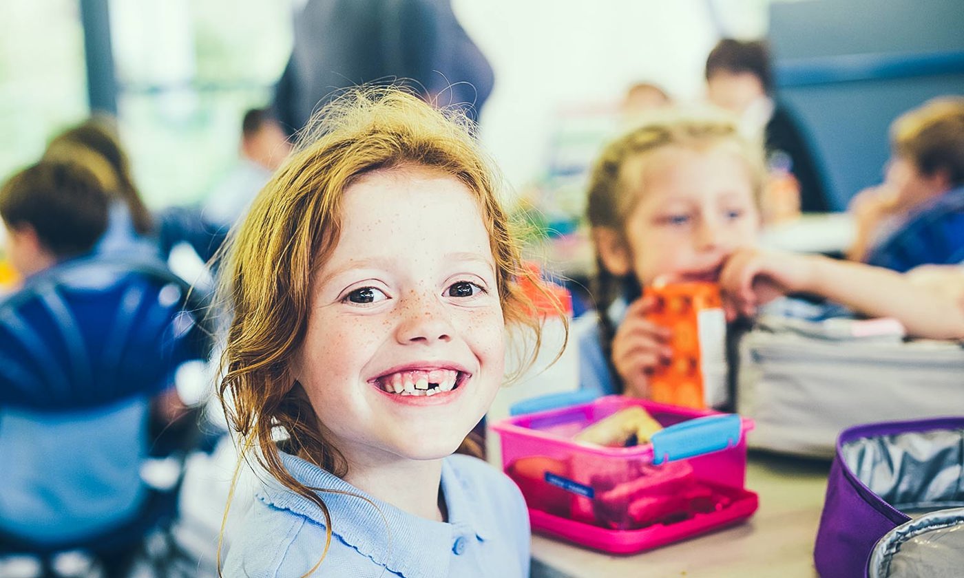 Smiling girl with a missing tooth with a healthy lunch