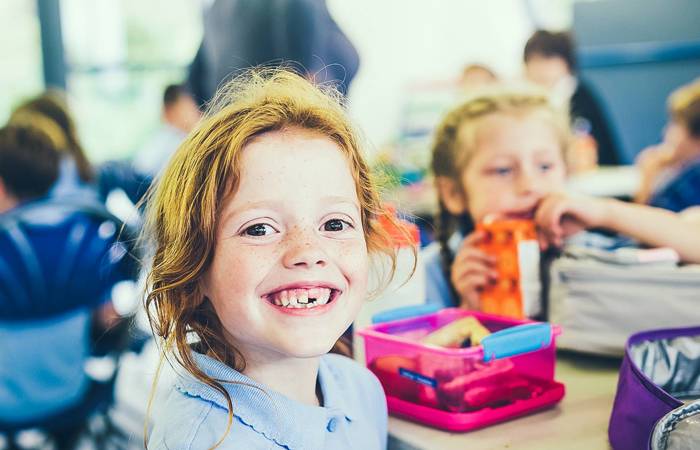 Smiling girl with a missing tooth with a healthy lunch