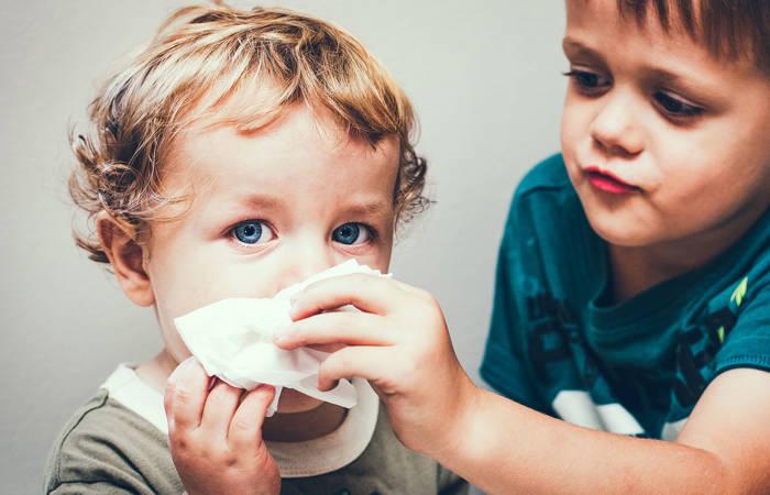 Older boy helping younger blow his nose
