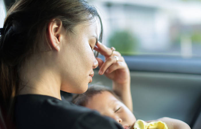 An exhausted mum trying to take a nap with her baby