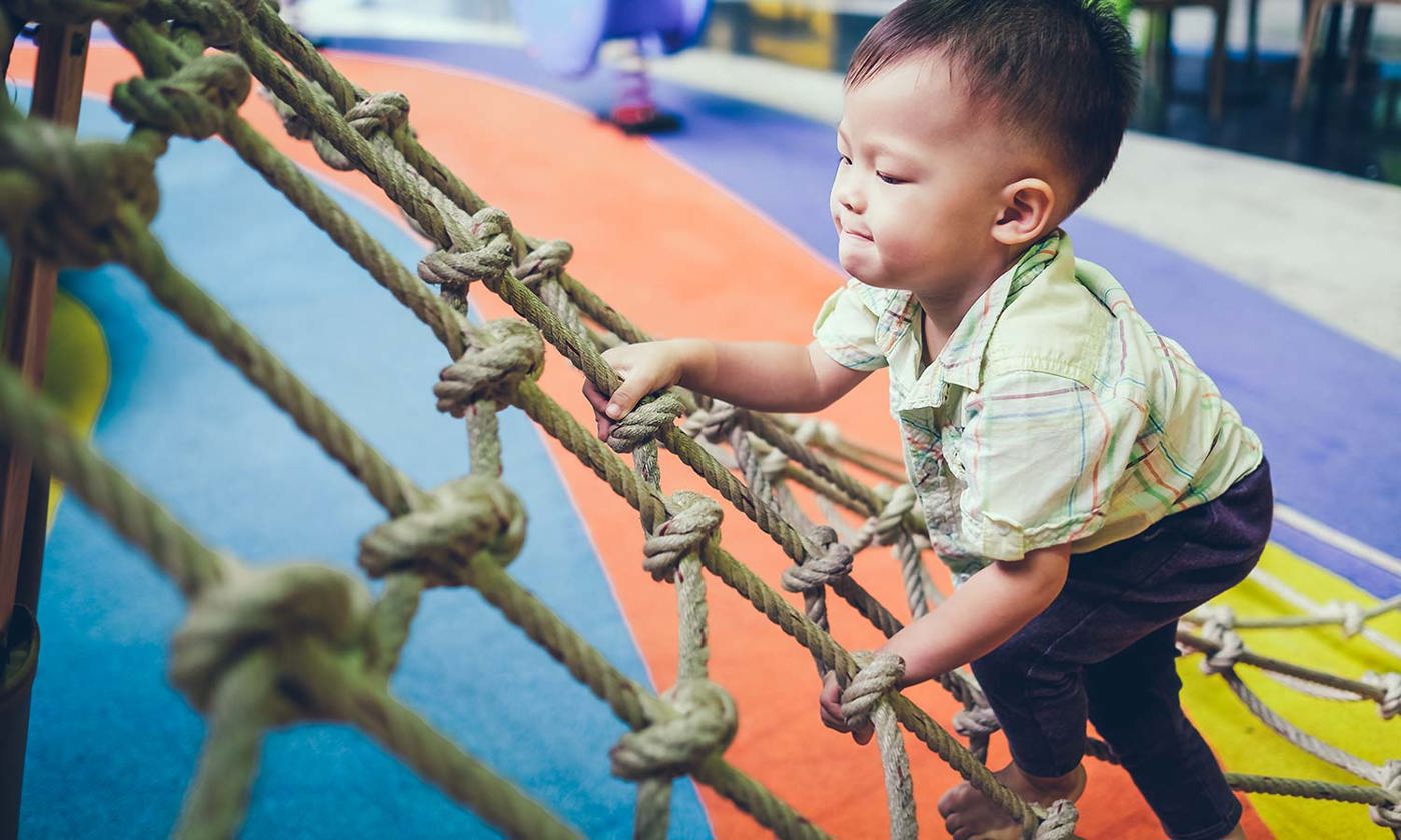 Child climbing a jungle gym at an indoor playground