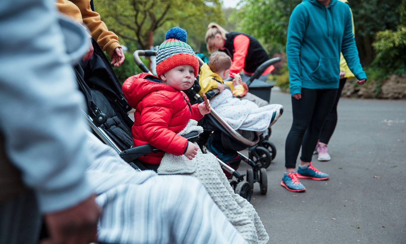 Agroup of mothers in the park with their children in baby strollers