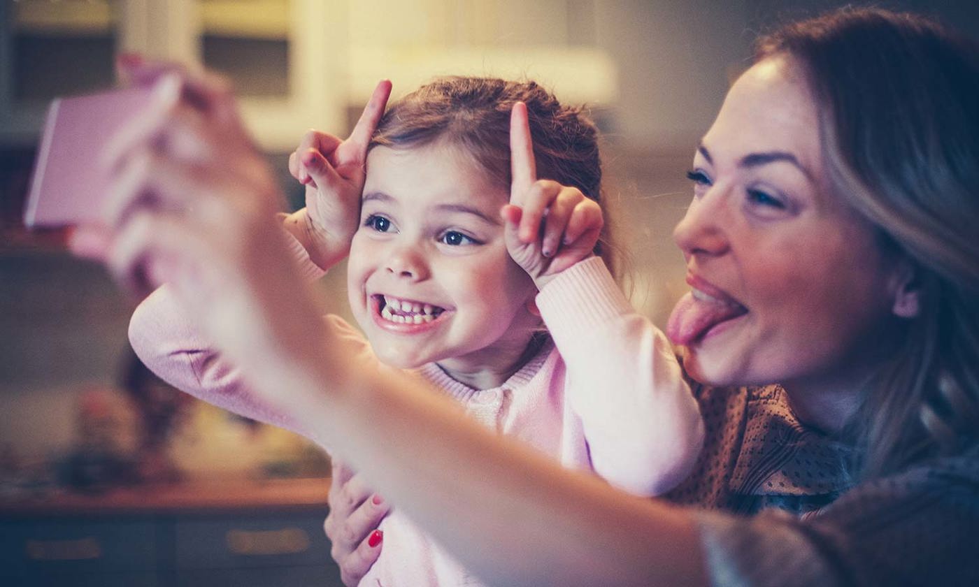 Mother and daughter photographing funny faces