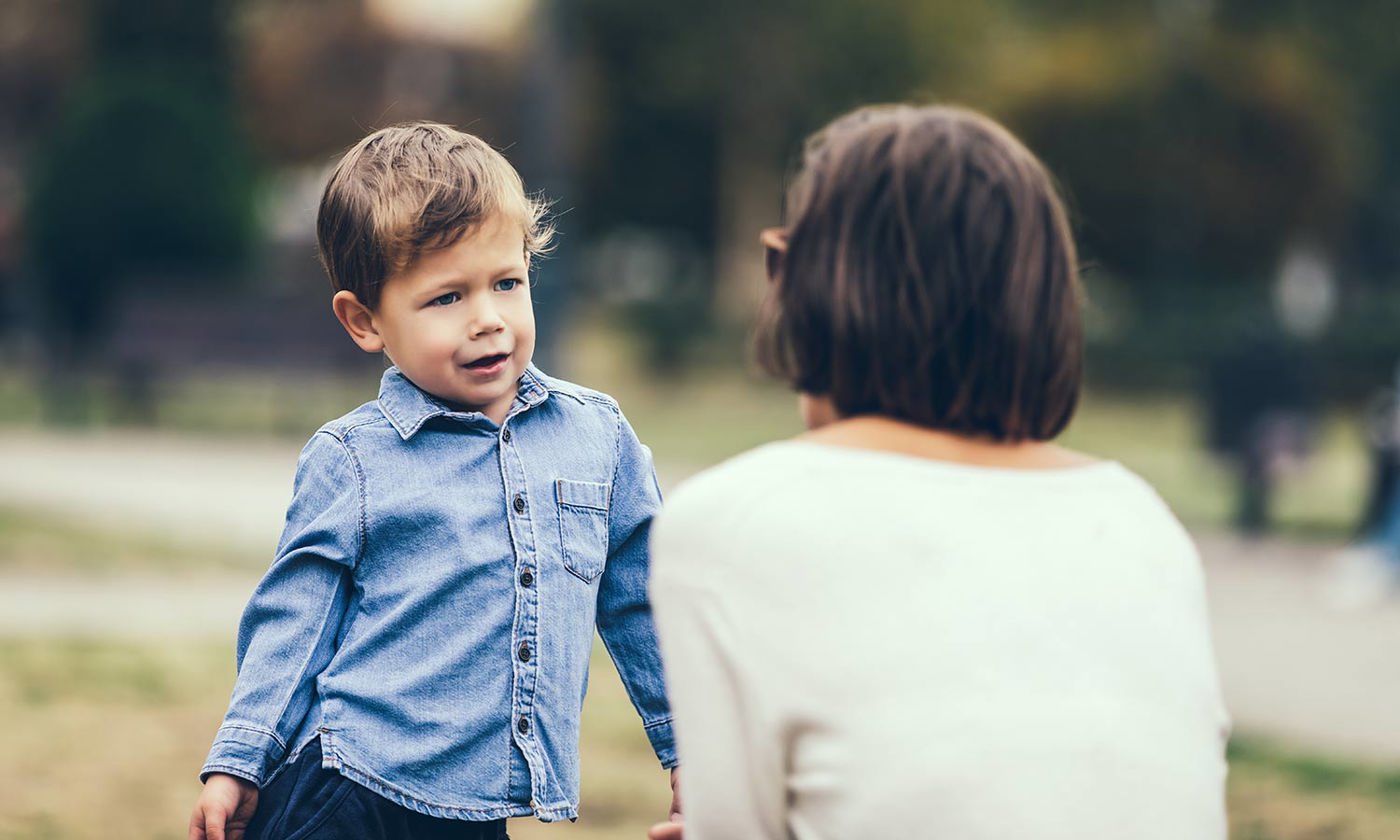 Cute little boy complaining to mother outdoors