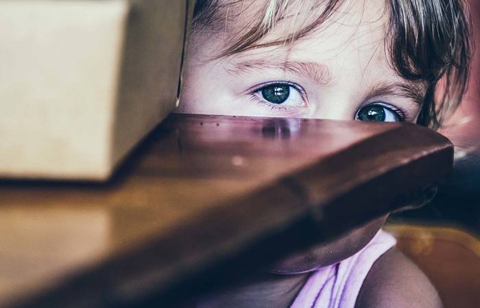 Small girl hiding behind a table