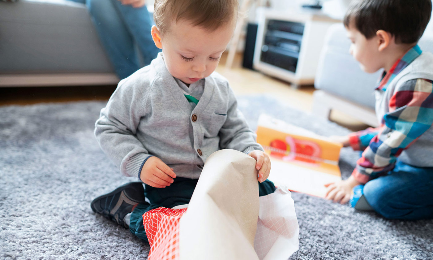 Two boys sitting on the floor and opening presents.