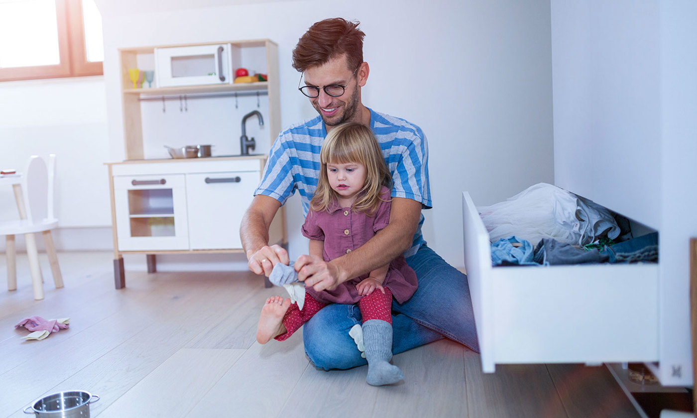 Dad is helping toddler daughter to get dressed