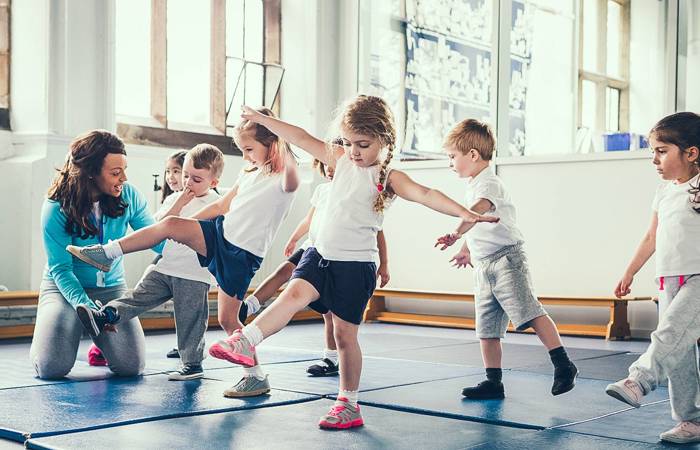 Small children learning to balance encouraged by a teacher