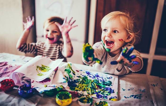 Cheerful children having fun doing finger painting