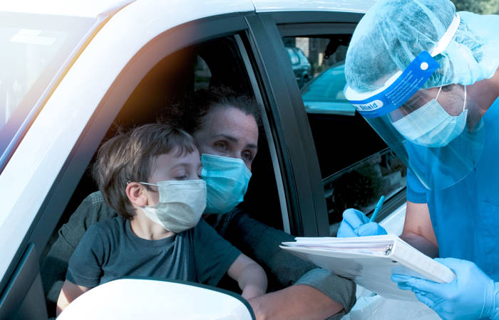 Healthcare worker performing a Covid-19 test to a woman and her son