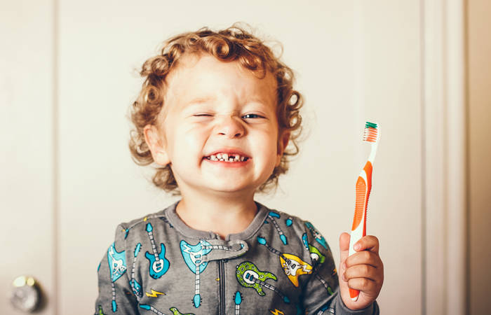 Toddler smiling while holding a toothbrush