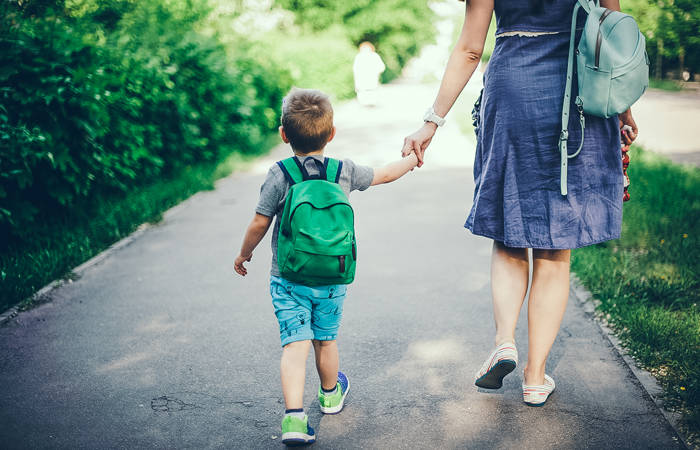 Back view of mother walking down the street with son