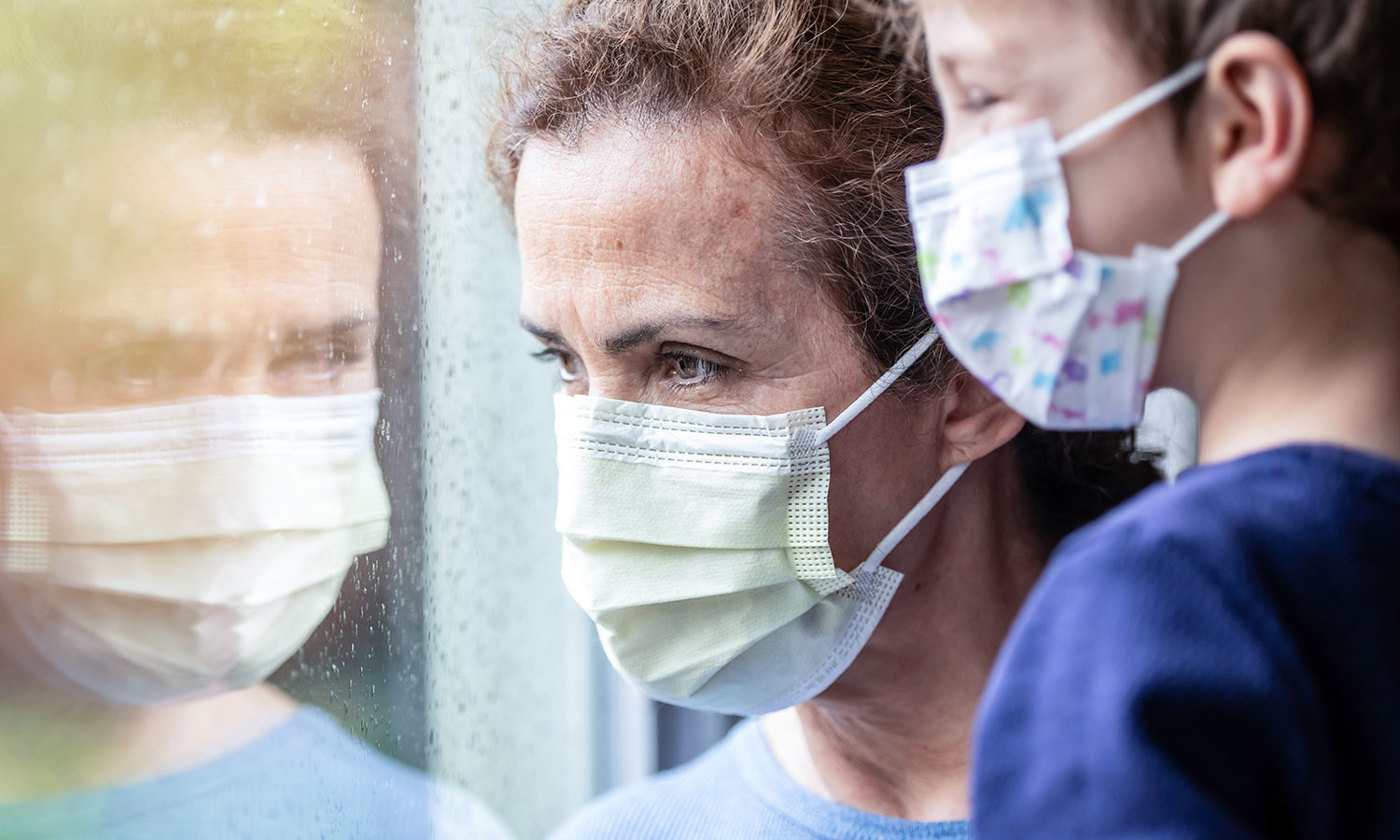 Woman posing with her son, both wearing protective masks