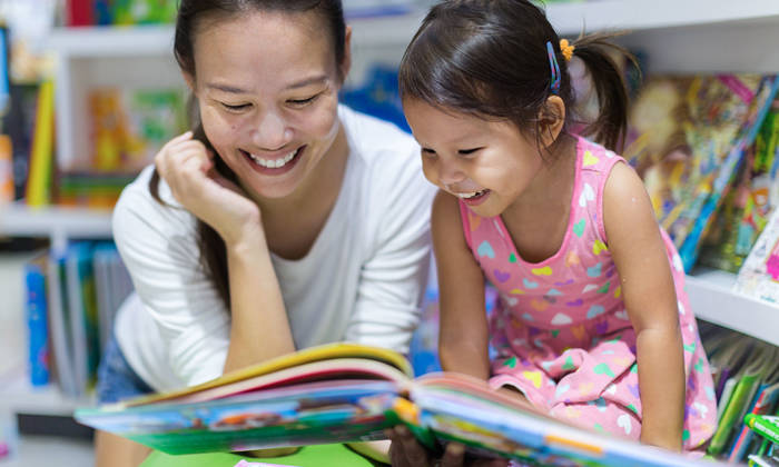 Teacher reading a educational book to her female student