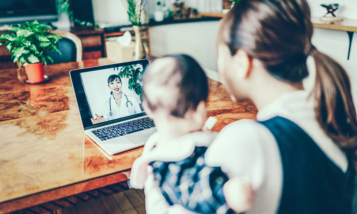 Mother and baby looking at a doctor on a computer