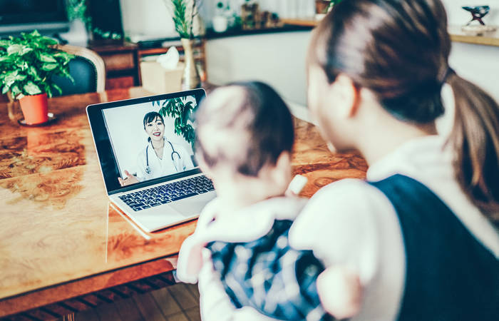 Mother and baby looking at a doctor on a computer