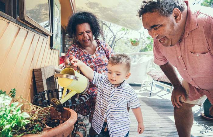 Baby boy watering plants with grandparents